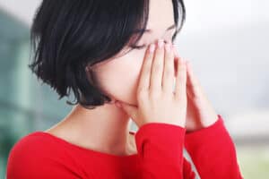 Picture of a woman with a sinus infection closing her eyes and holding the bridge of her nose in pain.