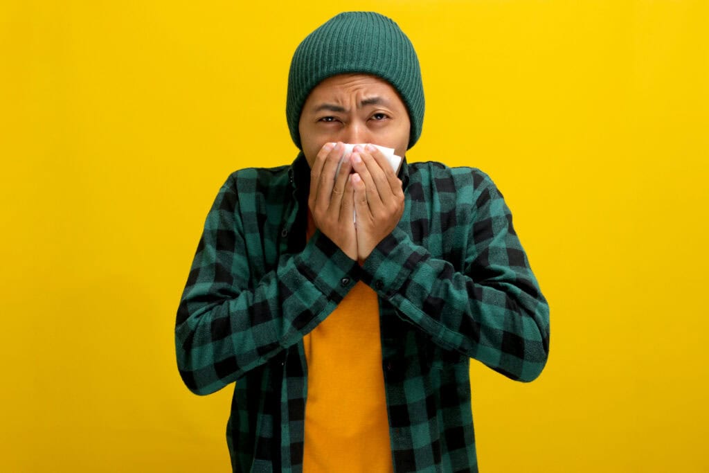 man sneezing into tissue